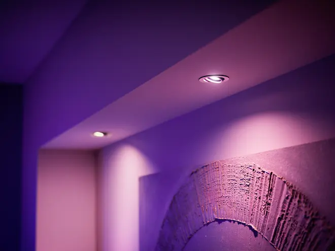 Indbyggede loftsspots udsender blødt lilla lys og oplyser et moderne interiør med tekstureret vægkunst. Perfekt til stemningsbelysning i stuer, gange eller moderne rum.