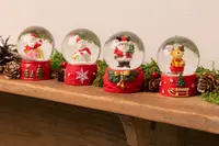 Fyra juliga snöglober med tomte, snögubbe, björn och ren i glaskupor, alla med röd bas dekorerad med julmotiv.