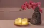 Set med fyra flamfria LED-ljus på träbricka, tillsammans med en Buddha-staty i sten och rosa konstgjorda orkidéblommor, perfekt för heminredning och lugn stämning.