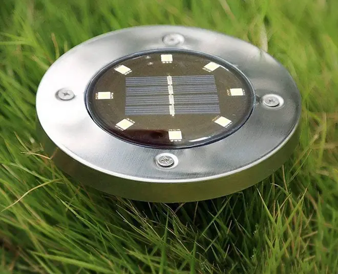 Rund solcellsdriven trädgårdslampa i rostfritt stål med åtta LED-lampor, avsedd för markmontering. Väderbeständig, passar gångvägar, gräsmattor eller uteplatser.