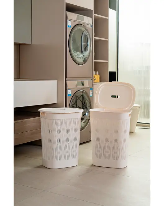 Två vita tvättkorgar i plast med dekorativa utskärningar, en med öppet lock och en stängd. Rektangulär form, bärhandtag på sidorna, modern stil.