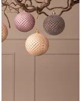 Set med tre texturerade julgranskulor i rosa, grått och kräm, med geometriskt diamantmönster och guldupphängning, perfekta för julgransdekoration.