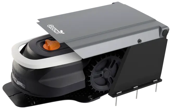 Robotplæneklipper i sort og grå beskyttelsesladestation med delvist dækket top, stort sidehjul og synlig orange tænd/sluk-knap. Vejrbestandigt design til udendørs brug.