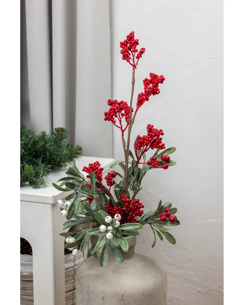 Konstgjord julbukett med röda och vita bär, gröna blad och bruna stjälkar i en neutral vas. Passar som festlig dekoration eller bordsarrangemang.