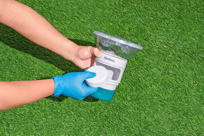 Bestway pool kemikaliedispenser med gennemsigtigt låg, blå bund og justerbar kontrolring. Vises med en rund klortablet, ideel til vedligeholdelse af poolvandets renhed.