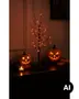 Halloween bordtræ med LED-grene og orange lys, vist med lysende græskarlygter og et fyrfadslys på en mørk hylde. - Billedet er skabt med AI