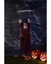Hängande Halloween-dekoration med skrämmande marionettdocka, lysande röda ögon, röd klänning, omgiven av konstgjorda spindelnät och två upplysta pumpalyktor.
