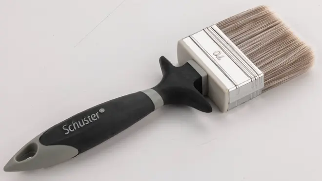 Bred malerpensel med syntetiske børster, ergonomisk sort og gråt håndtag samt ophængshul. Velegnet til maling af store flader. Mærket 'Schuster' på håndtaget.