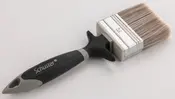 Bred malerpensel med syntetiske børster, ergonomisk sort og gråt håndtag samt ophængshul. Velegnet til maling af store flader. Mærket 'Schuster' på håndtaget.
