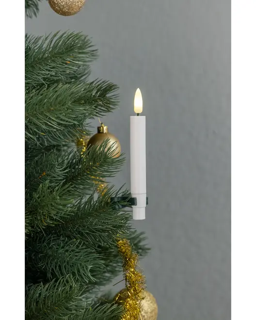 Batteridrevet LED-lys med hvidt stearinlys og varm gul flamme, fastgjort på en juletræsgren. Omgivet af grønne nåle, guldkugler og guldtinsel.