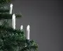 Sæt elektriske lys med hvide baser, fastgjort på kunstige grønne grene af juletræ, udsender varmt hvidt lys, ideel til indendørs juledekoration.
