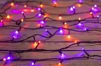 Ljusslinga med LED-lampor i orange och lila på svart sladd. Passar för inomhusdekoration, särskilt till Halloween eller festliga tillfällen. Lamporna är jämnt fördelade.