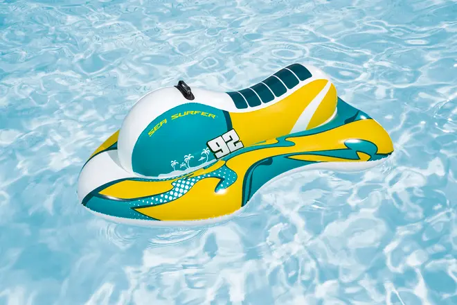 Uppblåsbar poolflytare formad som en vattenskoter, i gult, turkost och vitt, med texten "Sea Surfer 92" och ett svart handtag upptill.