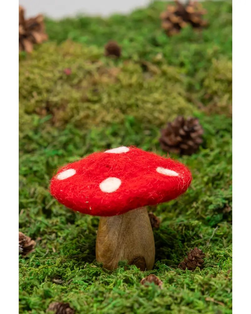 Dekorativ svampfigur med trästam och röd filtkeps med vita prickar, perfekt för heminredning eller sagoträdgårdar. Cirka 10 cm hög.