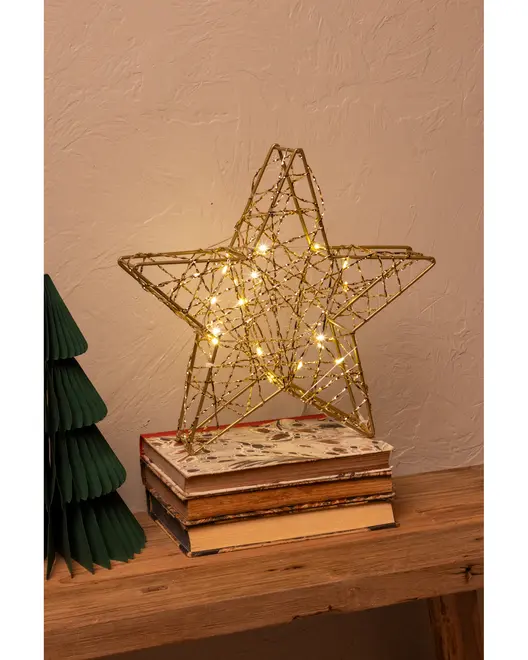 En dekorativ stjerneformet ornament lavet af gyldent tråd, med små varm-hvide LED-lys flettet ind i designet. Stjernen har et tredimensionelt udseende og står oprejst på en stak bøger. Den gyldne tråd giver et festligt og elegant udtryk, velegnet til jule- eller hjemmeudsmykning.