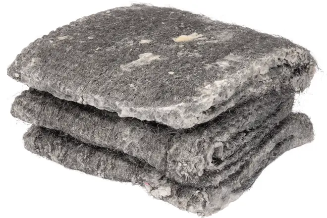 Sammenfoldet gråt filtunderlag med tyk, fibret struktur og synlige hvide og farvede pletter. Velegnet til gulvunderlag eller lydisolering, robust og egnet til byggeprojekter.