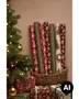 Assorterede juleindpakningsruller i rød, grøn, bordeaux og creme med festlige mønstre, placeret i en flettet kurv ved siden af et pyntet juletræ. - Billedet er skabt med AI