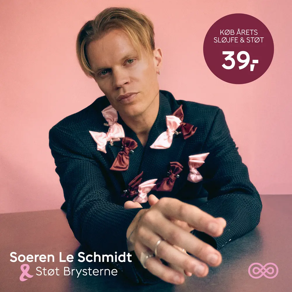 Mørk struktureret blazer dekoreret med flere lyserøde og bordeaux sløjfer, der støtter brystkræftsagen. Sløjferne er fastgjort foran og på ærmerne som pynt.