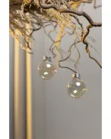 Set med två klara glasjulgranskulor med silverfästen, hängande i snören. Kulorna är runda, transparenta och har en subtil skimrande yta för festlig känsla.