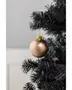 Guldglitrende julekugle med skinnende overflade, hængende på en sort kunstig juletræsgren. Har guldtop og snor til ophæng. Elegant julepynt.