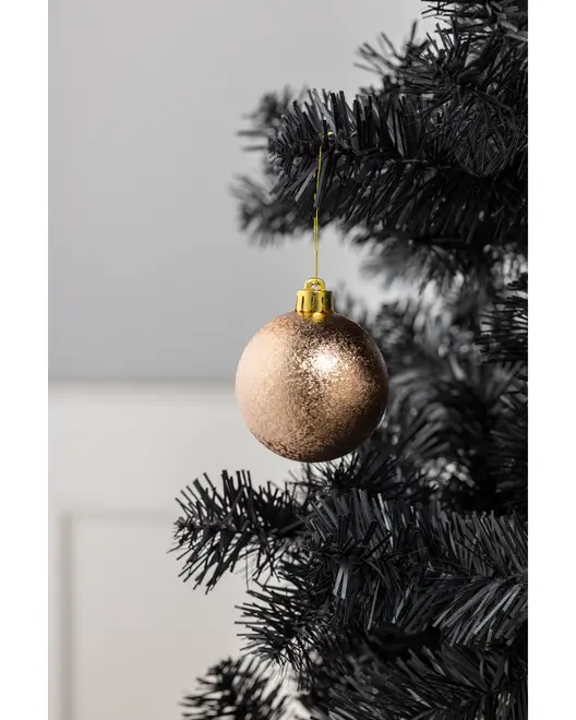 Guldglitrende julekugle med skinnende overflade, hængende på en sort kunstig juletræsgren. Har guldtop og snor til ophæng. Elegant julepynt.