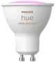 Philips Hue GU10 smart LED-pære, hvid og farve, kompakt spotdesign, hvidt kabinet, sølv GU10-fatning, justerbar belysning, kompatibel med smart home-systemer.