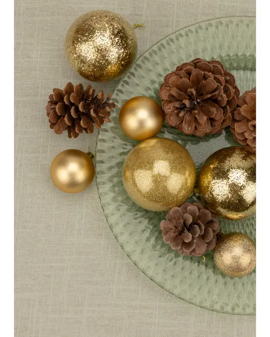 Set med gyllene julgranskulor i matt och glitter, tillsammans med naturliga bruna kottar på en texturerad glasplatta. Perfekt för festlig dekoration.