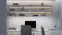 Moderne hjemmekontor med computer, tastatur og mus på hvidt skrivebord, grå stol, svævende hylder med bøger, dekoration og blødt LED-lys. Minimalistisk og organiseret arbejdsplads.