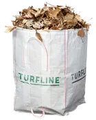 Stor hvid vævet polypropylen havesæk med håndtag, mærket 'TURFLINE', fyldt med tørre brune blade. Velegnet til haveaffald, blade eller græsafklip.