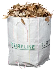 Stor vit vävd polypropen trädgårdssäck med handtag, märkt 'TURFLINE', fylld med torra bruna löv. Passar för trädgårdsavfall, löv eller gräsklipp.