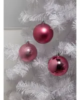 Set med tre rosa julgranskulor med matt, glittrig och blank yta, hängande i en vit konstgjord gran. Varje kula har silverfärgad upphängningskrok.