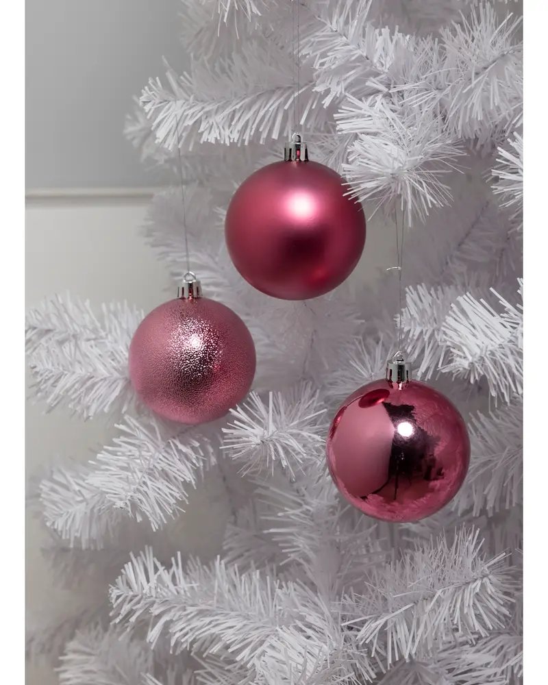 Set med tre rosa julgranskulor med matt, glittrig och blank yta, hängande i en vit konstgjord gran. Varje kula har silverfärgad upphängningskrok.