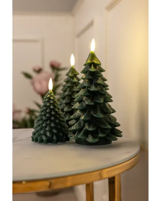 Sæt med tre grønne stearinlys formet som juletræer med realistisk flammeeffekt, placeret på et rundt marmorbord. Perfekt til juledekoration.