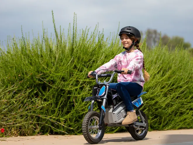 Elektrisk børne-crossmotorcykel med sort og blå design, grove dæk og nummerplade. Robust stel, komfortabelt sæde og håndtag. Velegnet til udendørs kørsel, sikkerhedshjelm medfølger.