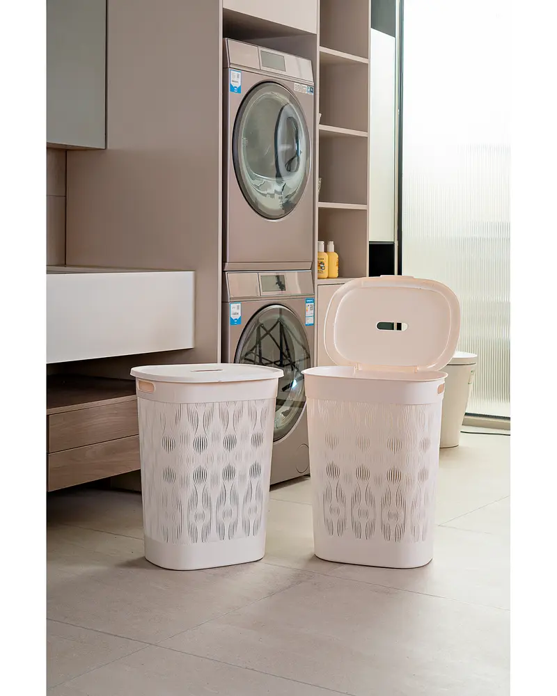 Set med två beige tvättkorgar i plast med dekorativa utskärningar, en med stängt lock och en öppen. Båda har sidhandtag och ventilationshål.