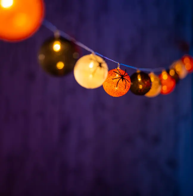 Ljusslinga med runda bollar i orange, svart och vitt. Vissa bollar har spindelmönster. Passar till Halloween och ger en mysig, kuslig stämning inomhus.