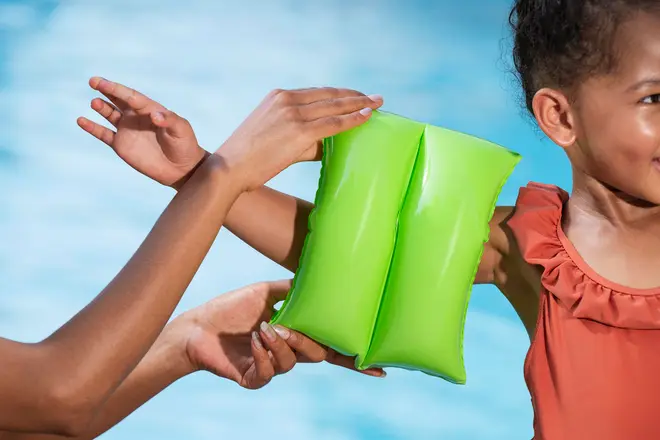 Lys grøn oppustelig svømmearmbånd til børn, vist på overarmen. Fremstillet af holdbar plast, designet til opdrift og sikkerhed ved vandaktiviteter.