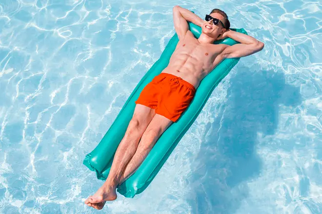 Turkos uppblåsbar poolmadrass med konturerad design, passar vuxna. Ger bekväm stöd för avkoppling i vatten. Hållbar, lätt och enkel att blåsa upp. Visas med man.