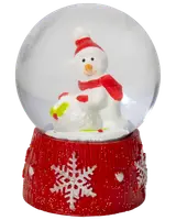 Glas-snöglob med snögubbe i röd mössa och halsduk, håller en snöboll. Röd bas med vita snöflingor och glitter. Festlig juldekoration.