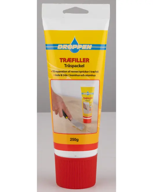 En 250g tube med gul og hvid etiket samt rød låg. Etiketten har blå og rød tekst samt et billede, der viser en hånd, der bruger en spartel til at påføre produktet på en træoverflade. Emballagen angiver, at det er egnet til reparation af revner i træ, både indendørs og udendørs.