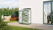 Kompakt växthus i glas med grön metallram, tre hyllor för växter, lutande tak och klara paneler. Passar utomhus, perfekt för små trädgårdar eller uteplatser.