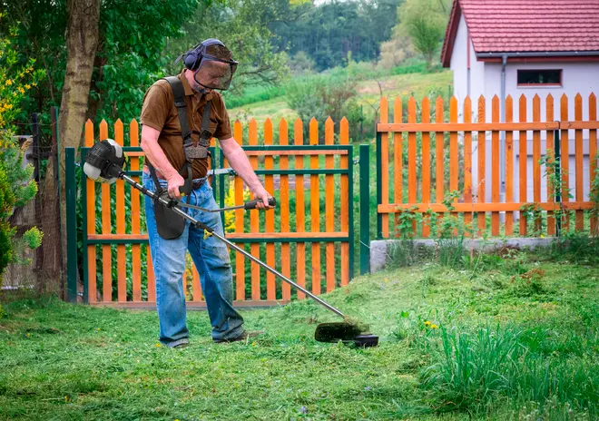 Benzindrevet græstrimmer med langt skaft, ergonomisk håndtag og skuldersele. Velegnet til at klippe græs og ukrudt i haver eller udendørs områder.