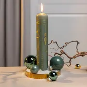 Grøn adventslys med guldnumre og julemotiver, omgivet af grønne glaskugler, kunstig sne og guldbakke. Dekorativ gren medfølger. Perfekt som juleborddekoration.