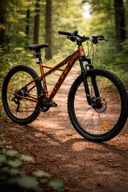 Mountainbike med robust orange stel, affjedret forgaffel, grove dæk til terræn, fladt styr, skivebremser og komfortabelt sadel. Velegnet til stier og ujævnt terræn.