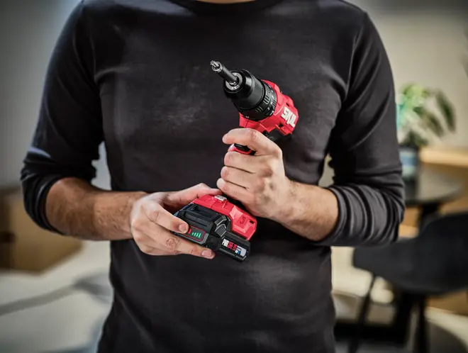 Trådløs rød og sort boremaskine med ergonomisk greb, LED-batteriindikator og nøglefri borepatron. Kompakt design, velegnet til hjemmet eller professionel brug.