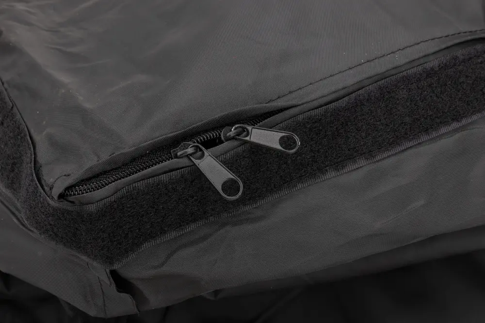 Närbild av svart tygväska med två dragkedjor och en kardborreremsa för säker stängning och enkel åtkomst till innehållet.
