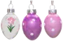 Set med tre äggformade glaspynt med silvertoppar: en vit med rosa blomma, en lila med vita prickar och en rosa med vita prickar. Blank yta.
