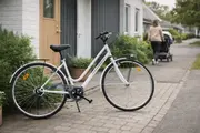 Hvid cykel står på fliser foran rækkehus