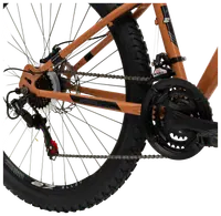 Närbild av mountainbikens bakhjul med Shimano-växelsystem, grovt mönstrat däck, aluminiumfälg, kedja och orange ram. Passar för terrängcykling och hållbarhet.