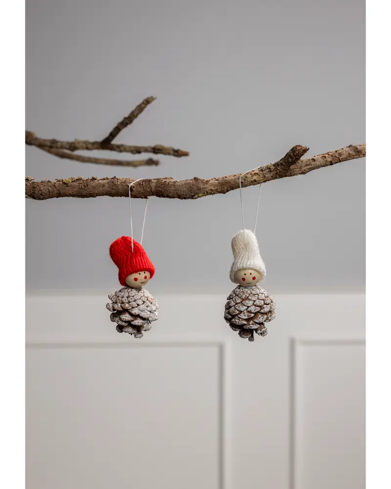 Två juldekorationer med kottkroppar, trähuvuden och stickade mössor—en röd, en vit. Hängs i snöre, perfekta för julgranen.